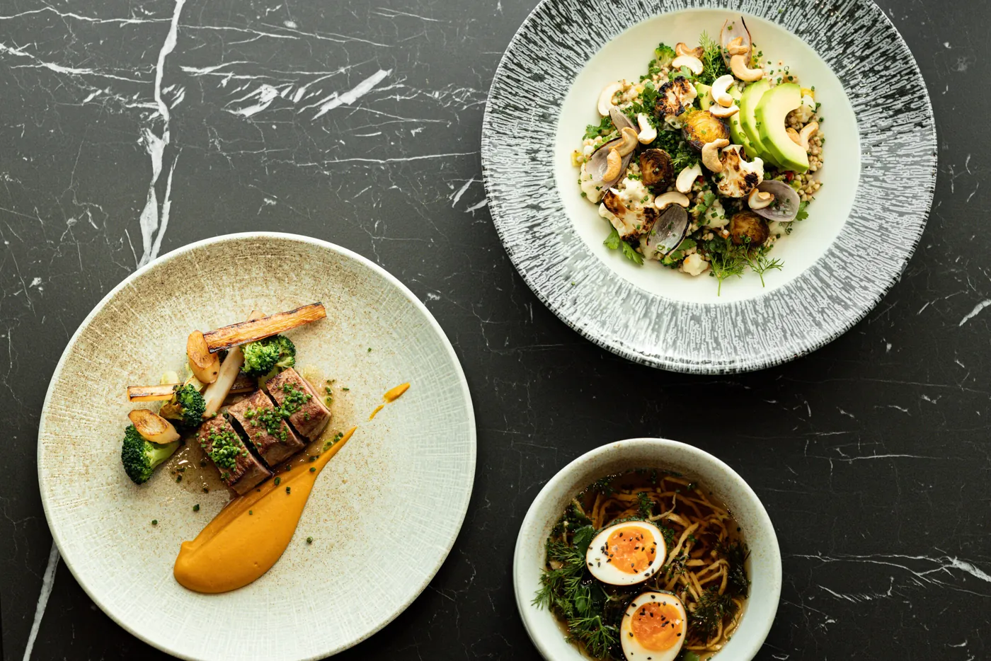 Three dishes from the Melea kitchen on a marble table