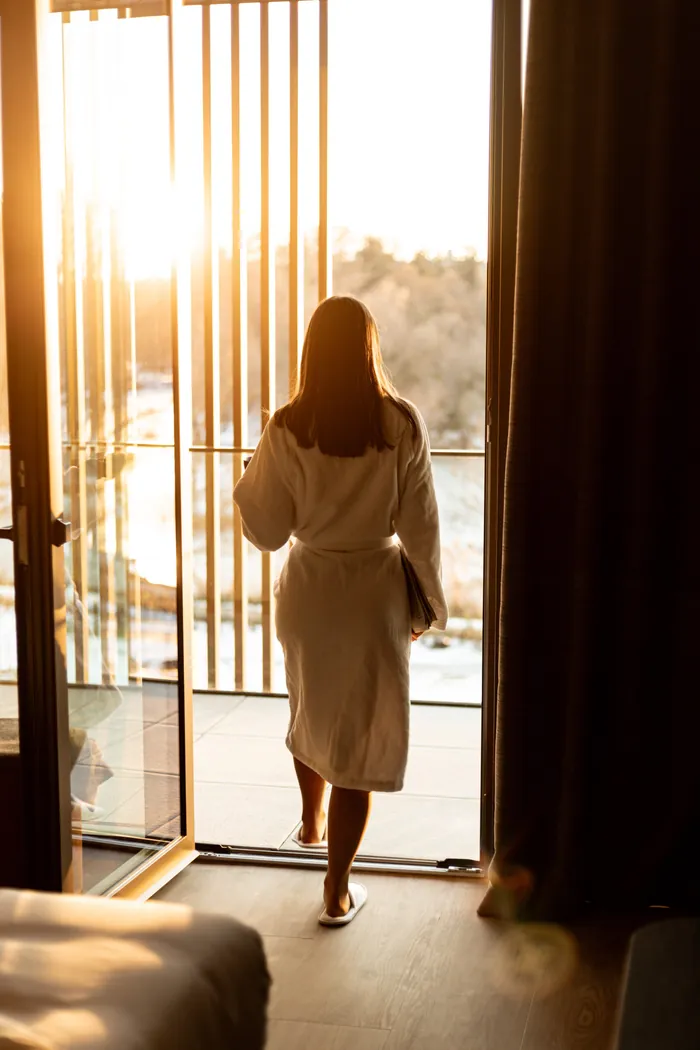 A guest in a robe stepping out onto a Melea balcony